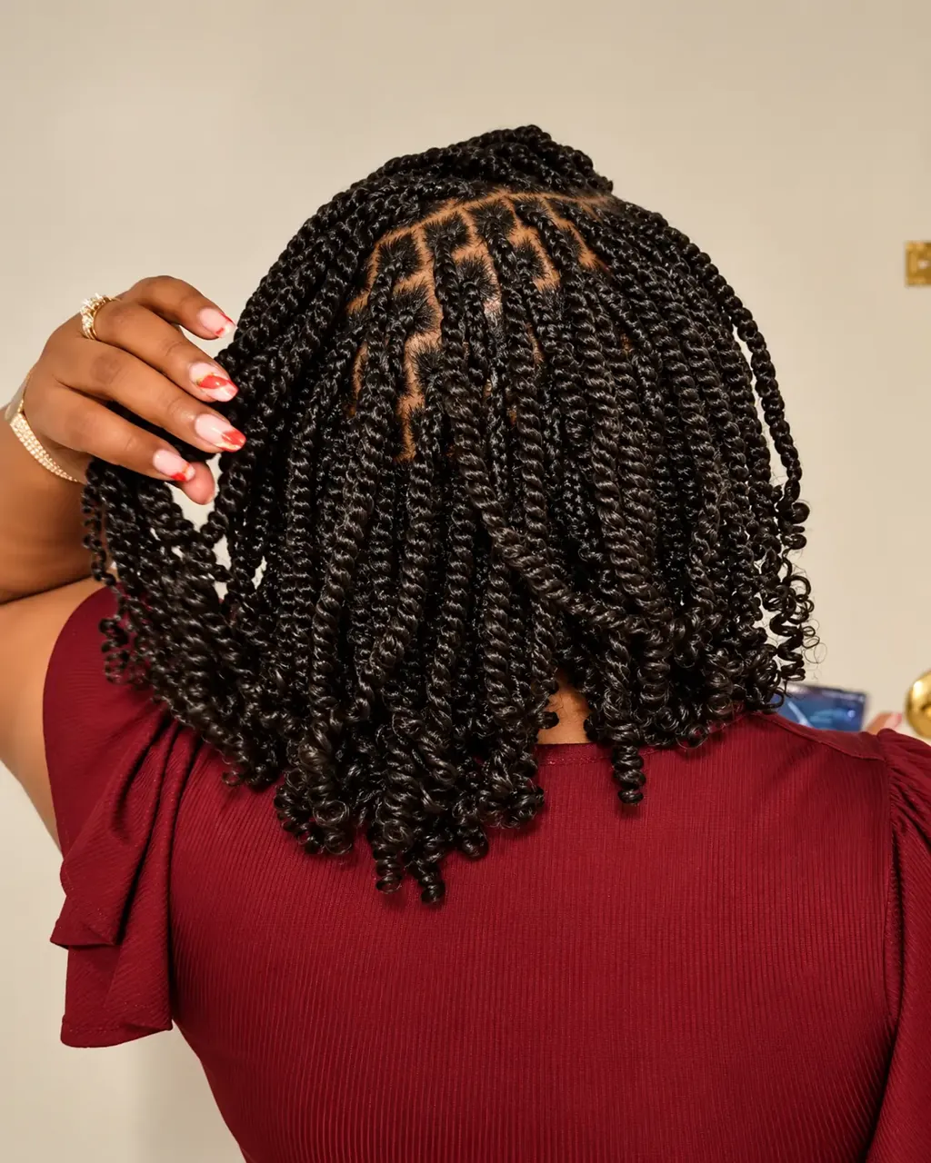 Short passion twists with visible square parting, hand lifting the twists